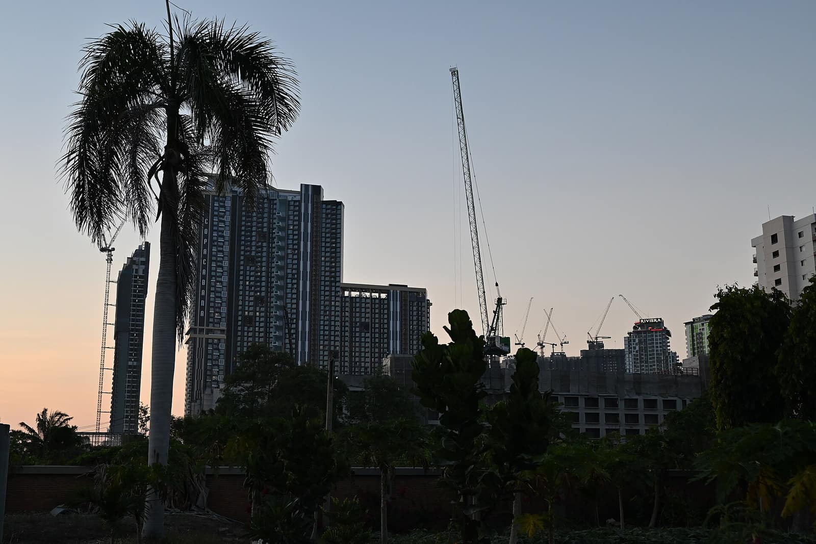 Construction cranes above a developing city skyline